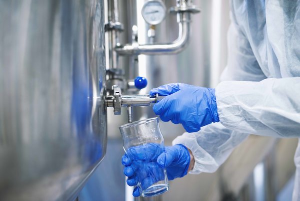 close_up_view_hands_protective_gloves_opening_tap_valve_filling_glass_with_samples_from_industria...